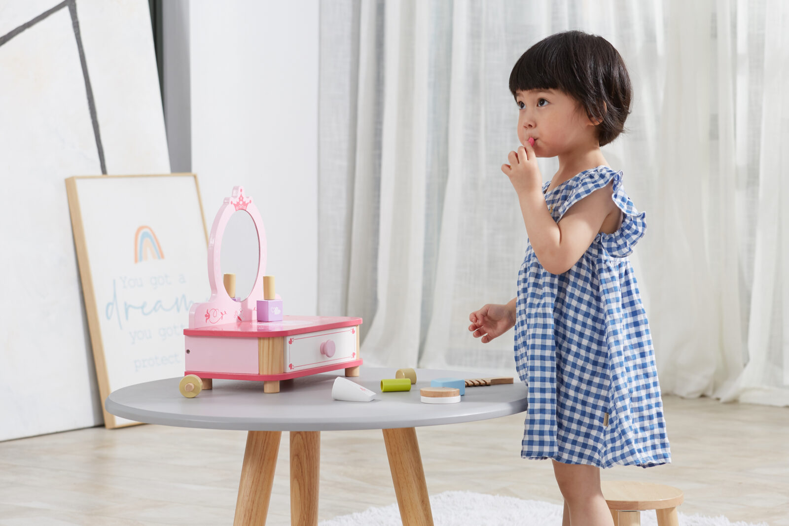 little girl using the wooden lip stick for the dressing table