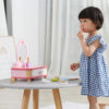 little girl using the wooden lip stick for the dressing table