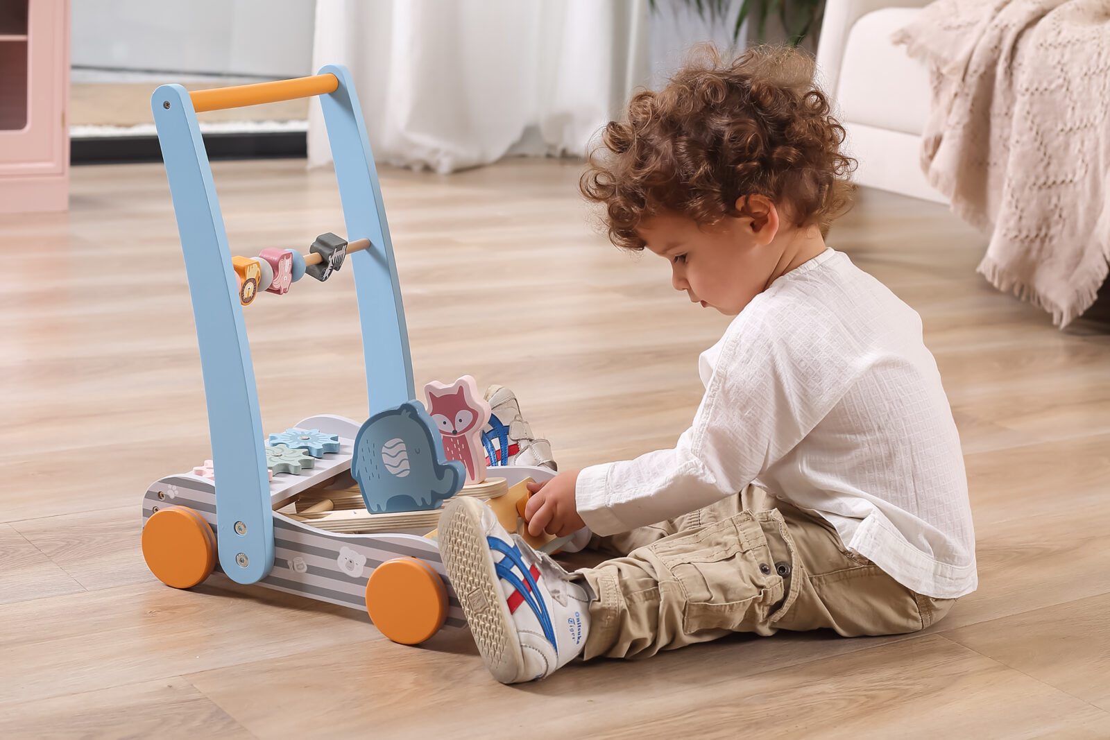 Child palying with soft toned baby walker featureing cute animal friends
